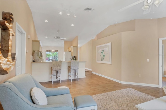 living room featuring lofted ceiling, ceiling fan, and light wood-type flooring