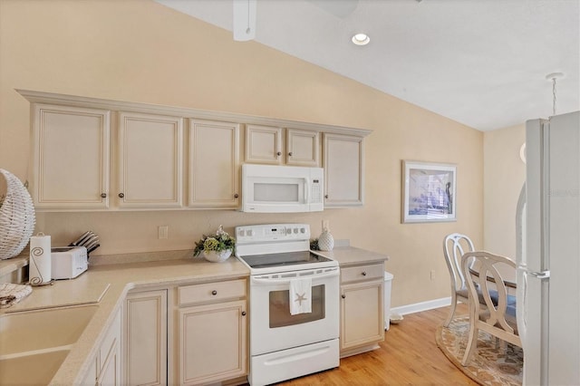 kitchen featuring lofted ceiling, sink, white appliances, light hardwood / wood-style flooring, and cream cabinetry