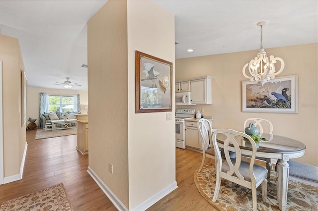 dining space featuring ceiling fan with notable chandelier and light wood-type flooring