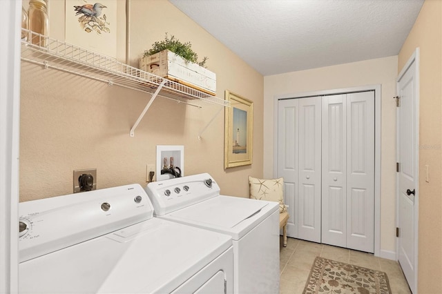 laundry area featuring light tile patterned floors, washer and clothes dryer, and a textured ceiling