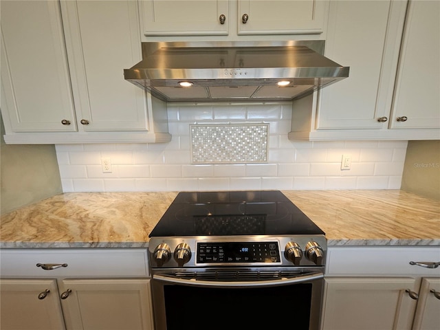 kitchen featuring decorative backsplash, electric stove, light stone counters, and island exhaust hood