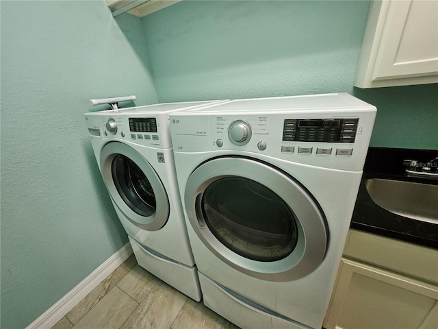 washroom featuring sink, cabinets, and washer and clothes dryer