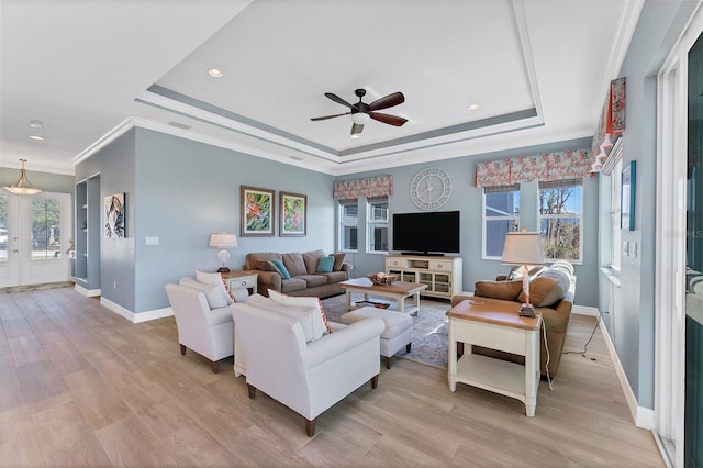 living room featuring ceiling fan, light hardwood / wood-style floors, a raised ceiling, and a wealth of natural light