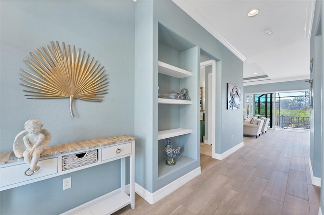 corridor with light hardwood / wood-style flooring, built in features, and ornamental molding