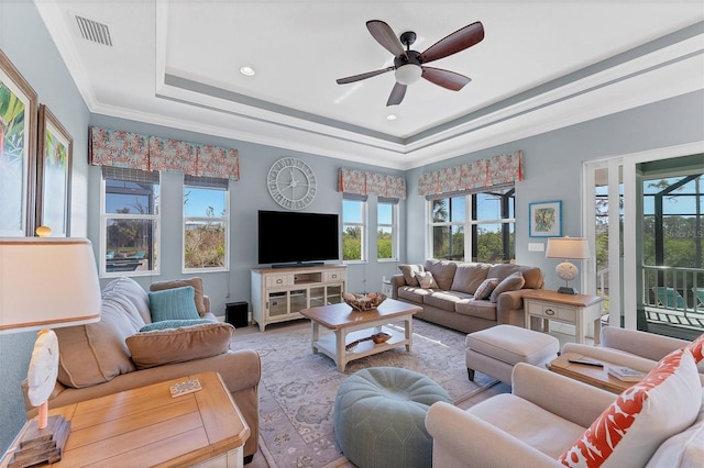 living room with ornamental molding, ceiling fan, and a raised ceiling