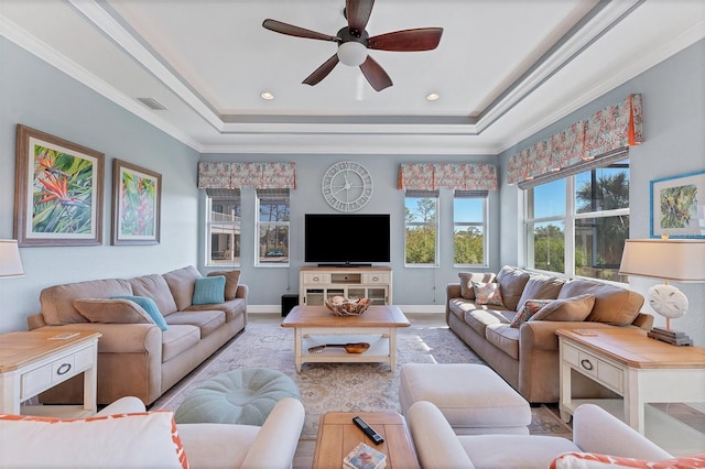 living room with a tray ceiling, ornamental molding, and ceiling fan