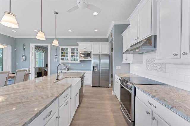 8025 Weyers Ct, Englewood, FL 34224 - kitchen featuring appliances with stainless steel finishes, under cabinet range hood, a sink, white cabinetry, and ornamental molding