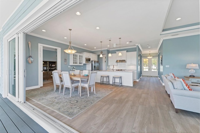 dining area featuring french doors, sink, light hardwood / wood-style flooring, and ornamental molding