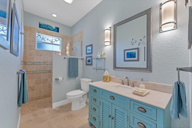 bathroom with tile patterned floors, a tile shower, vanity, and toilet