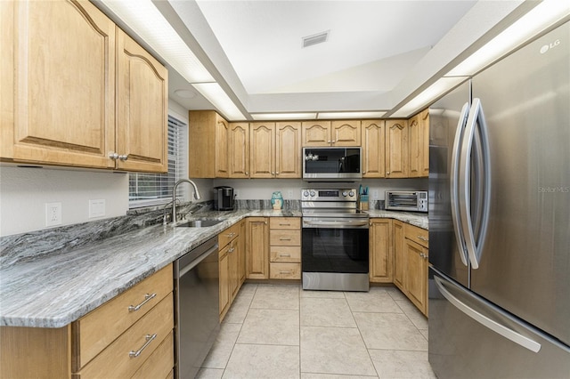 kitchen featuring sink, stainless steel appliances, light stone counters, vaulted ceiling, and light tile patterned flooring