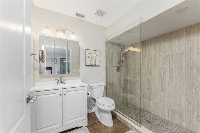 bathroom featuring a tile shower, vanity, hardwood / wood-style flooring, and toilet