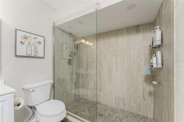 bathroom with toilet, vanity, and tiled shower