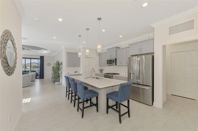 kitchen with a kitchen island with sink, hanging light fixtures, sink, gray cabinets, and stainless steel appliances