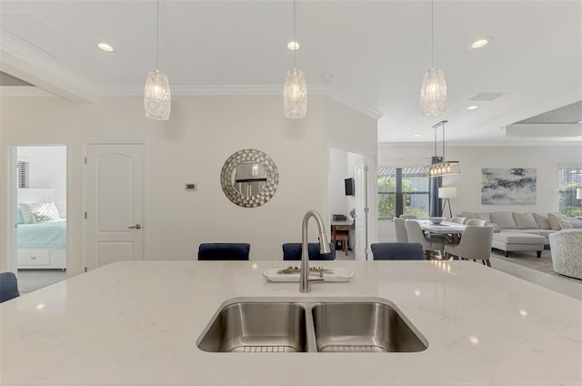 kitchen with crown molding, light stone counters, sink, and hanging light fixtures