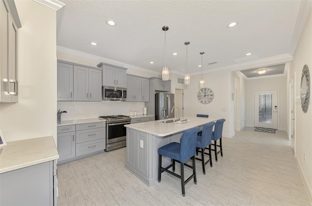 kitchen featuring appliances with stainless steel finishes, a kitchen island with sink, pendant lighting, and gray cabinetry