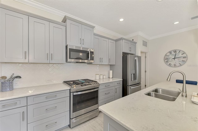 kitchen featuring gray cabinetry, light stone countertops, sink, appliances with stainless steel finishes, and ornamental molding