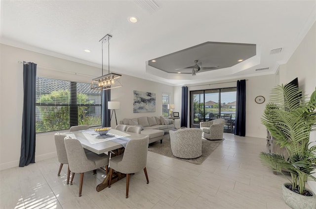 dining area with a raised ceiling, ceiling fan, and ornamental molding