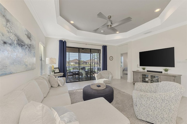 living room featuring a raised ceiling, ceiling fan, and ornamental molding