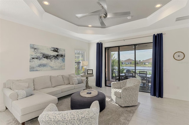 living room with a raised ceiling, ceiling fan, and ornamental molding