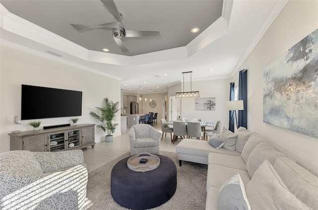 living room with a raised ceiling, ceiling fan, light hardwood / wood-style flooring, and ornamental molding