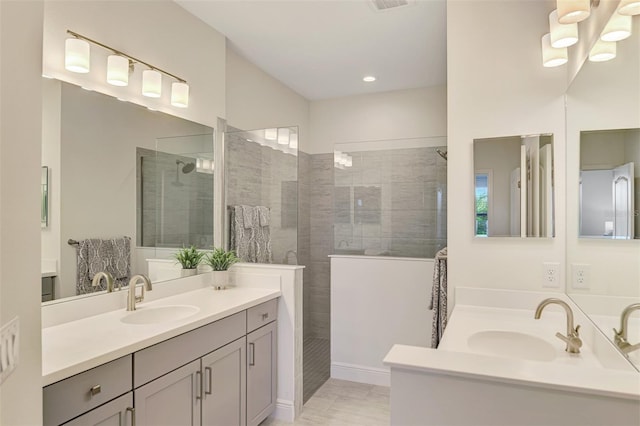 bathroom featuring a tile shower, vanity, and a notable chandelier