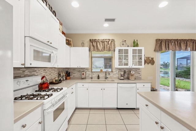 kitchen with sink, light tile patterned floors, crown molding, white appliances, and white cabinets