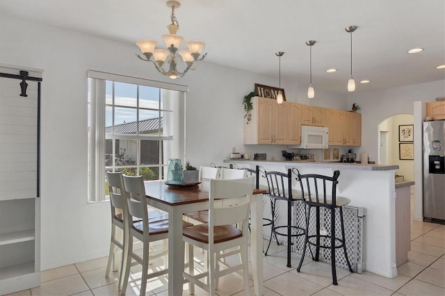 kitchen with stainless steel refrigerator with ice dispenser, light brown cabinets, light tile patterned floors, and a notable chandelier