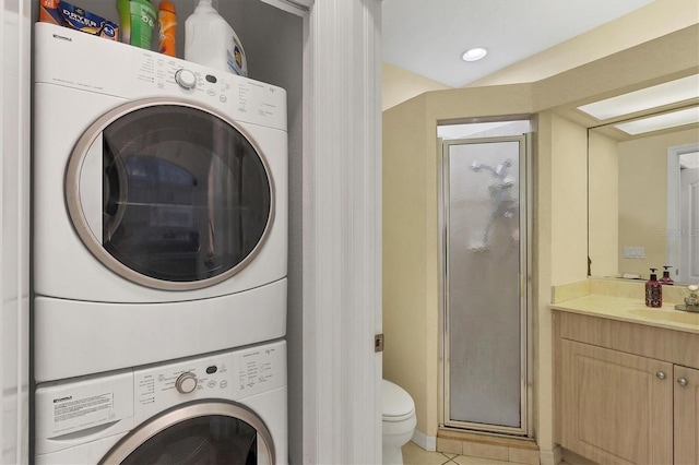 clothes washing area featuring light tile patterned floors, stacked washer and dryer, and sink