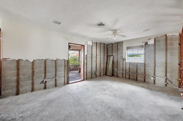 empty room featuring ceiling fan, concrete flooring, and a wealth of natural light