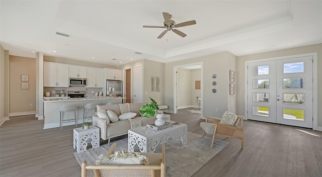 living room with ceiling fan, french doors, dark wood-type flooring, and a tray ceiling