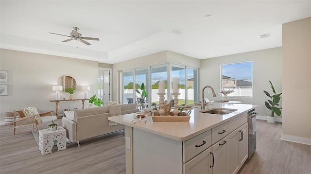 kitchen featuring a center island with sink, sink, stainless steel dishwasher, ceiling fan, and light hardwood / wood-style floors