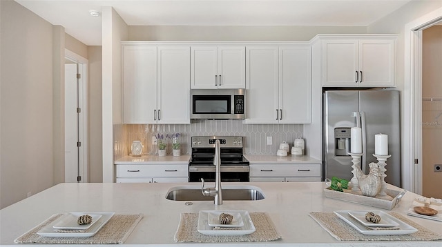 kitchen with white cabinets, appliances with stainless steel finishes, and backsplash