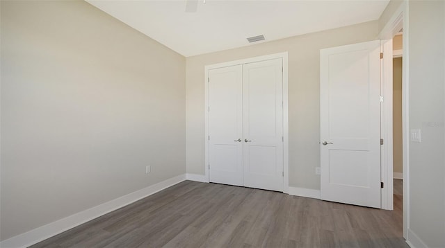 unfurnished bedroom with ceiling fan, light wood-type flooring, and a closet