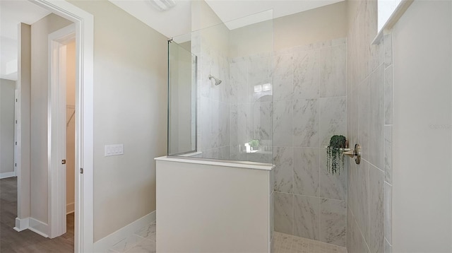 bathroom with a tile shower and hardwood / wood-style floors