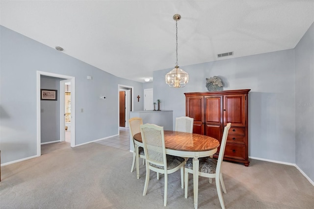 dining area featuring light carpet, a chandelier, and vaulted ceiling