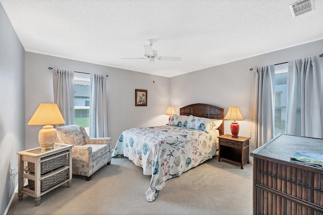 carpeted bedroom featuring ceiling fan and a textured ceiling