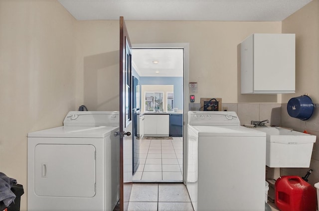 clothes washing area featuring light tile patterned flooring, separate washer and dryer, and sink