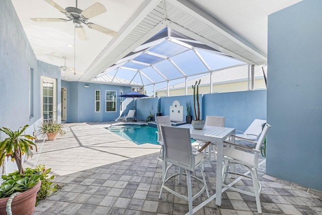 view of swimming pool with glass enclosure, ceiling fan, and a patio area