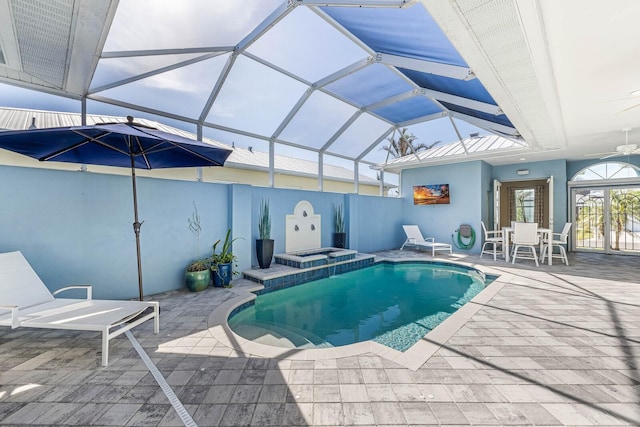 pool featuring glass enclosure, a patio, and an in ground hot tub