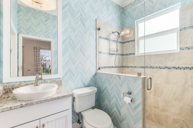 bathroom with a healthy amount of sunlight, a shower stall, toilet, and vanity