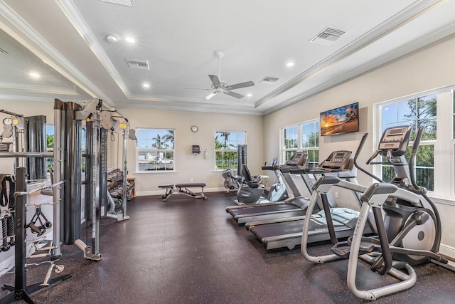 exercise room with ornamental molding, a raised ceiling, visible vents, and baseboards