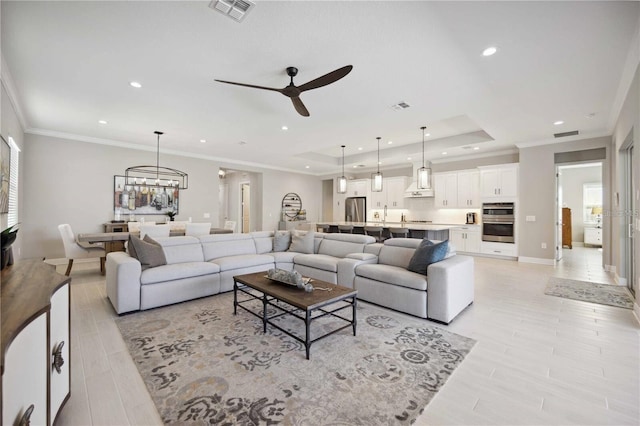 living room with crown molding, light hardwood / wood-style floors, and ceiling fan with notable chandelier