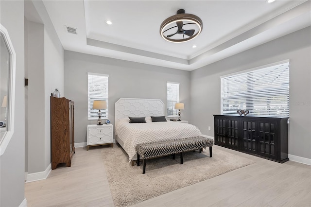 bedroom featuring a tray ceiling and light hardwood / wood-style floors