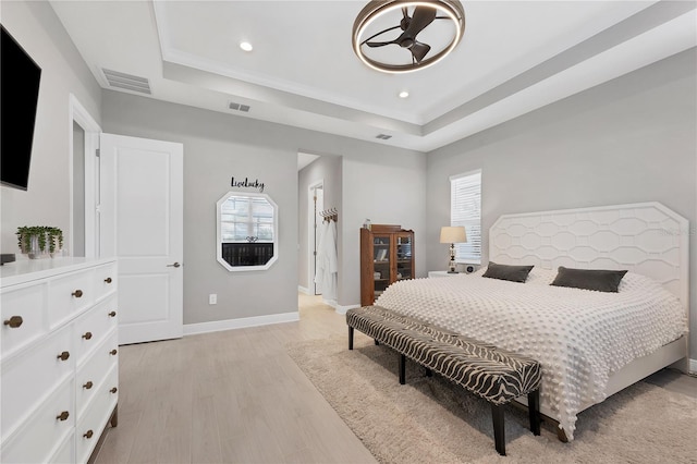 bedroom featuring a raised ceiling and light hardwood / wood-style flooring