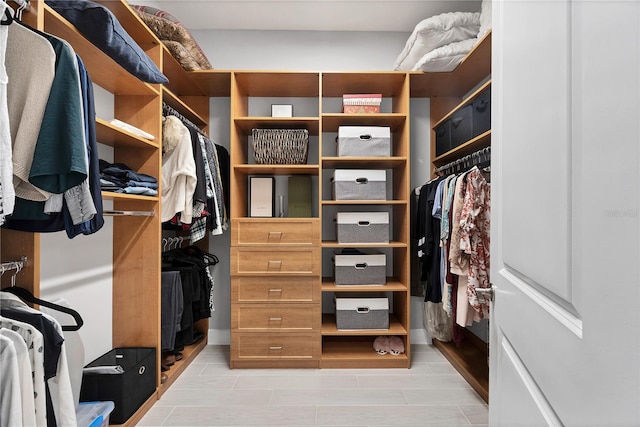 walk in closet with light hardwood / wood-style floors