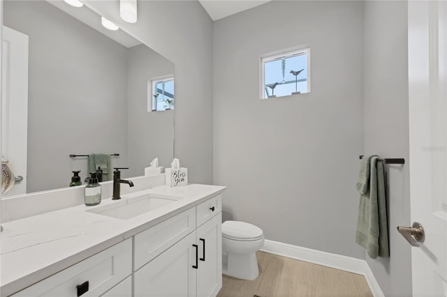 bathroom with hardwood / wood-style floors, vanity, a healthy amount of sunlight, and toilet