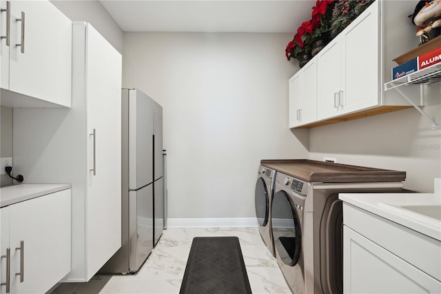 clothes washing area featuring washer and clothes dryer and cabinets