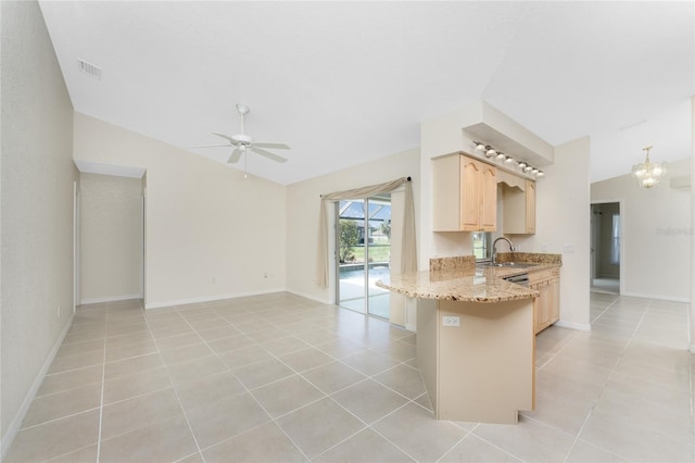 kitchen featuring lofted ceiling, light stone counters, kitchen peninsula, and light brown cabinetry