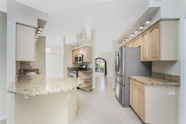 kitchen featuring kitchen peninsula, light stone countertops, stainless steel appliances, sink, and light brown cabinets