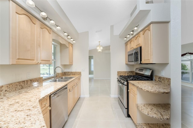 kitchen with light stone countertops, stainless steel appliances, light brown cabinetry, and vaulted ceiling